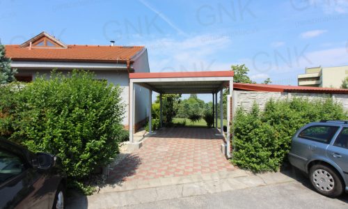 Ein montiertes Stahlcarport in grau mit einer ziegelroten Attika