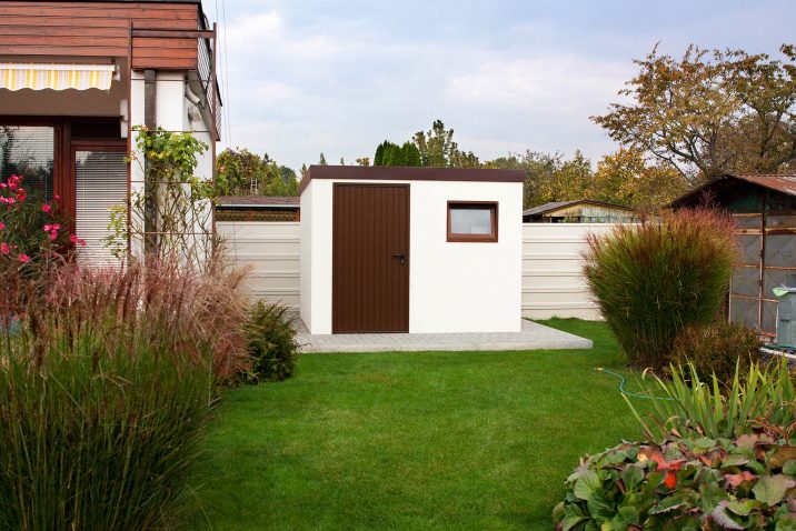 Ein Gartenhaus in weißer Farbe mit der Tür in braun