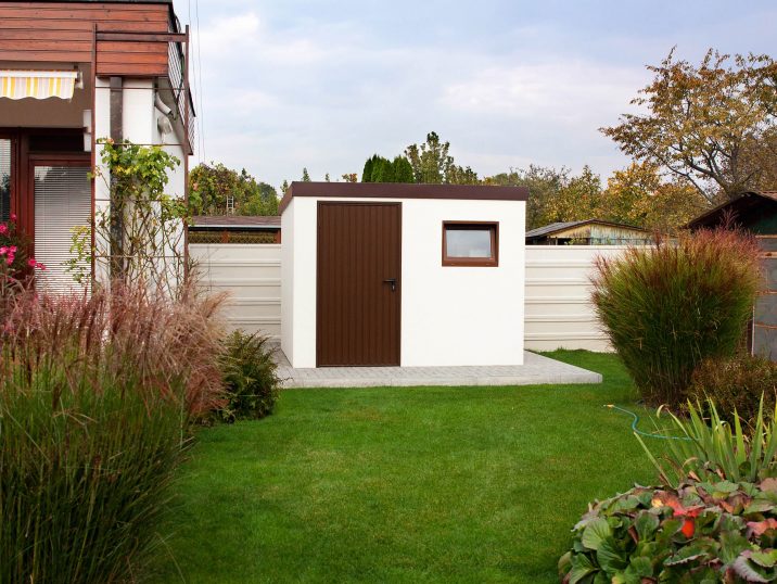 Ein Gartenhaus in weißer Farbe mit der Tür in braun