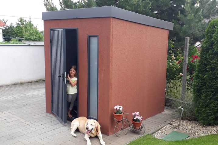 Braune Gartenhütte mit einer kleine Fräulein und dem Familienhund