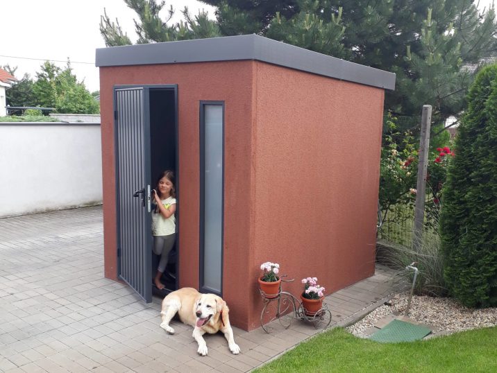 Braune Gartenhütte mit einer kleine Fräulein und dem Familienhund