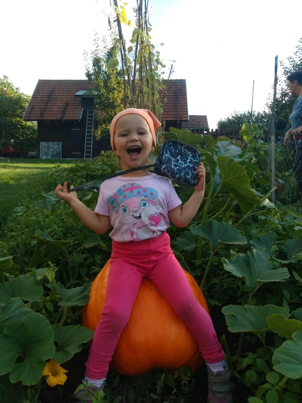 Ein lächelndes Mädchen sitz auf einem riesigen Kürbis