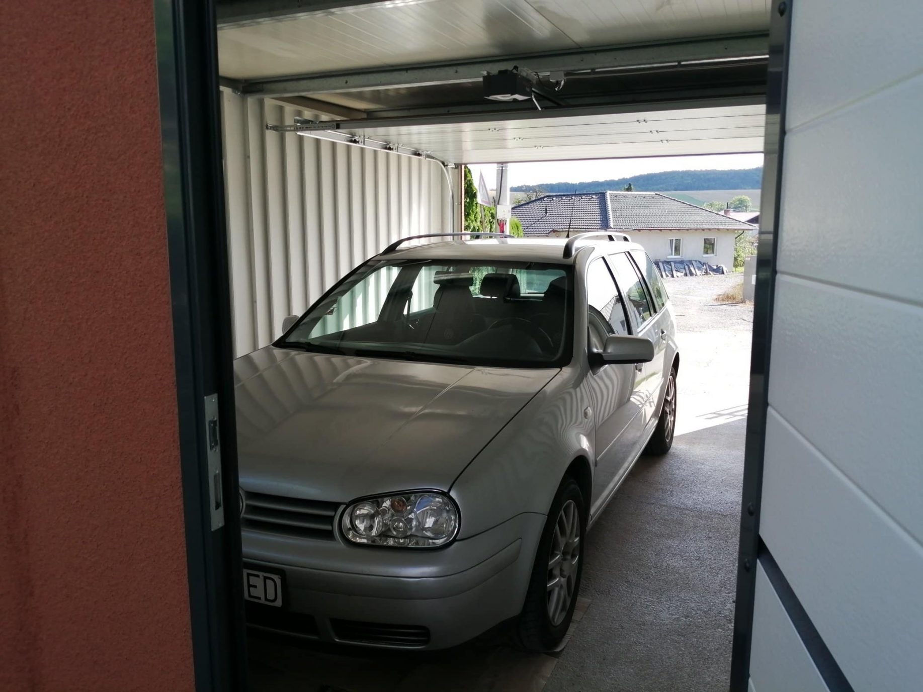 Ein Auto parkt in der ungedämmten Garage mit Durchgang ins Haus