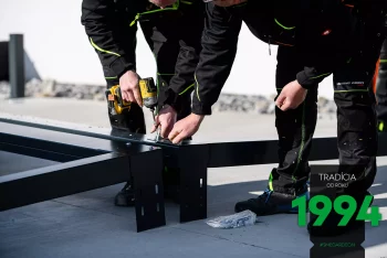 Es werden die ersten Elemente einer Stahlpergola zusammengeschraubt