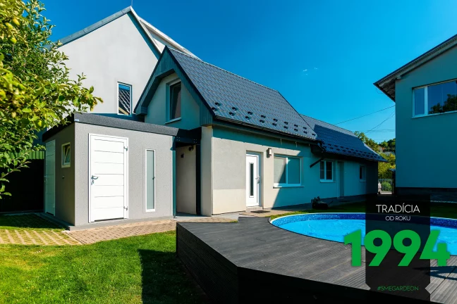Ein Gartenhäuschen mit Pultdach, angepasst zu einem Haus mit grauem Satteldach