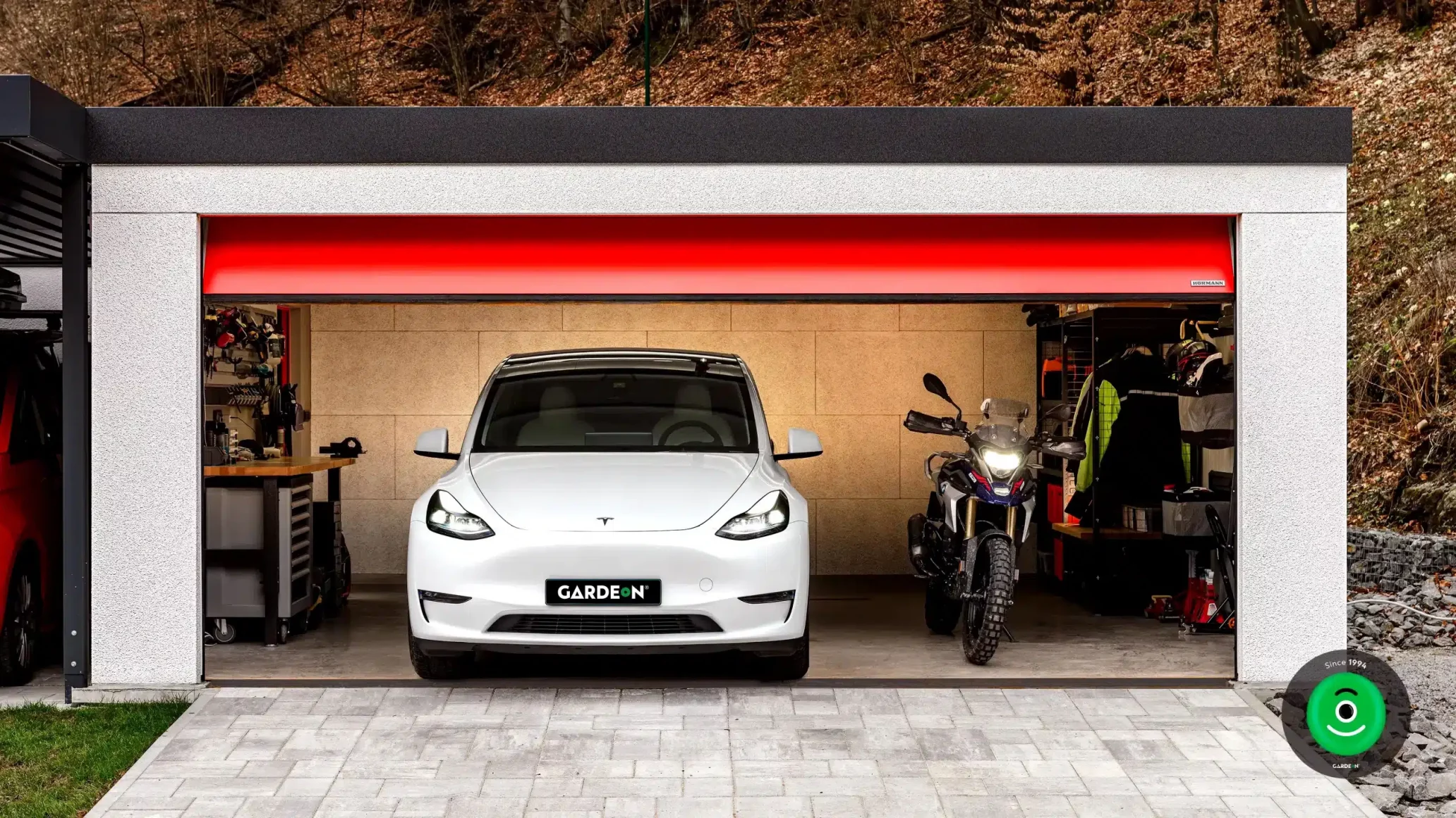 Tesla und Motorrad in der GARDEON-Garage mit rotem Tor