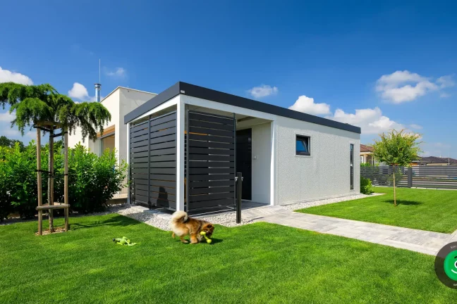 Ein kleiner Hund beim Gartenhaus mit einer Pergola