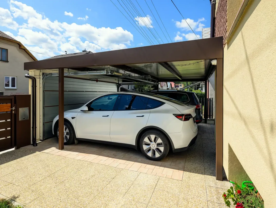 Autos geschützt unter einem Carport mit geschlossenem breitem Garagentor.