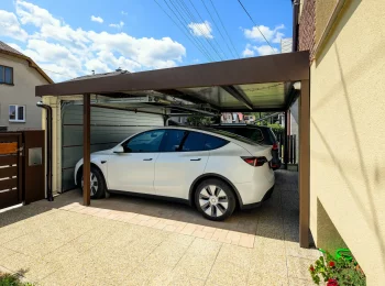 Autos geschützt unter einem Carport mit geschlossenem breitem Garagentor.