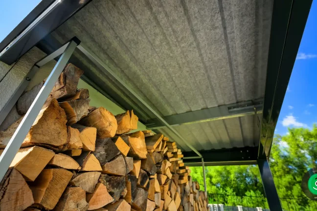 Holz wird unter einer Überdachung gelagert, geschützt vor Regen und Feuchtigkeit.