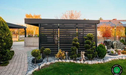 Seitenwand des Unterstands bei Ziergehölzen und Kies