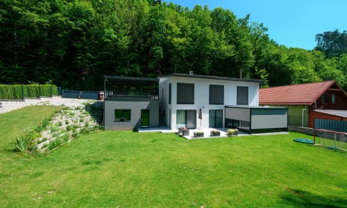 Seitliches Carport mit anthrazitfarbener Metallfüllung auf erhöhtem Untergrund.