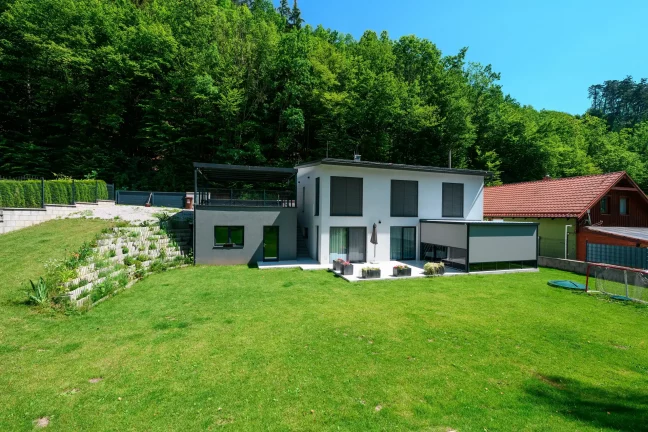 Seitliches Carport mit anthrazitfarbener Metallfüllung auf erhöhtem Untergrund.