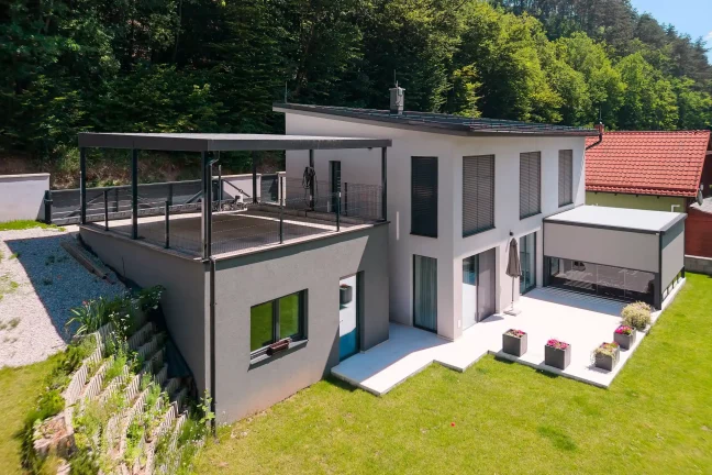 Anthrazitfarbenes Carport integriert auf einem erhöhten Untergrund.