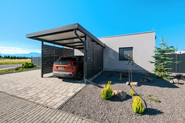 Anthrazitfarbenes Vordach mit Metallfüllung und geparktem SUV am Einfamilienhaus.