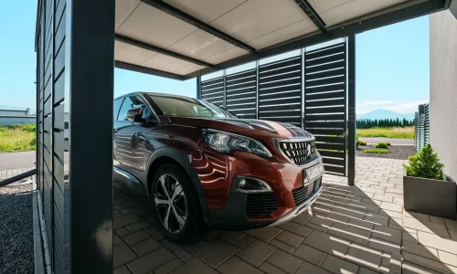 Vordach mit anthrazitfarbener Metallfüllung und parkendem SUV.