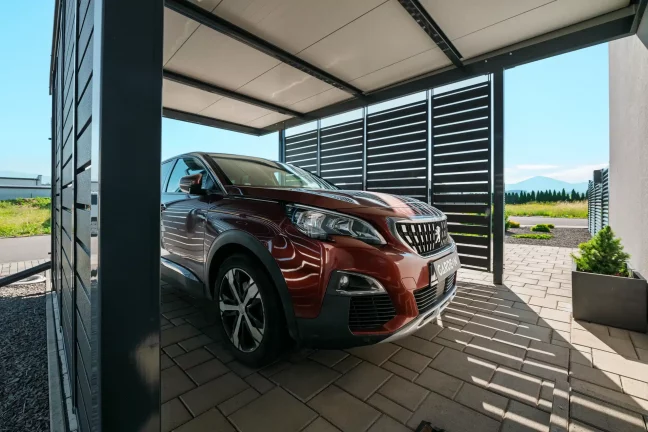 Vordach mit anthrazitfarbener Metallfüllung und parkendem SUV.