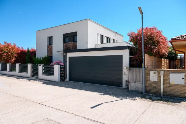 Moderner Carport mit Garagentor bei minimalistischem Einfamilienhaus