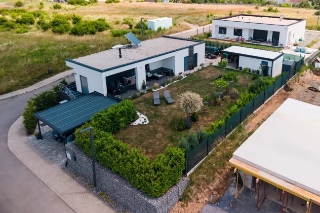 Luftaufnahme eines anthrazitfarbenen Carports am Haus mit gepflegtem Garten.