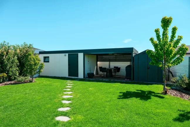 Modernes Gartenhaus mit Überdachung und großem grünen Garten