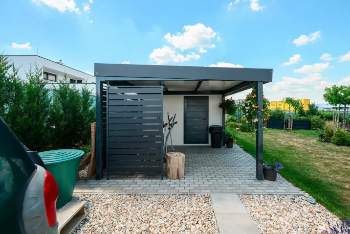 Metallverkleidung des anthrazitfarbenen Carports mit Seitenwand und Gartenhaus.