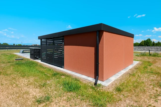 KABE Putz in Ziegelfarbe bedeckt die Wände des Gartenhauses mit Flachdach.