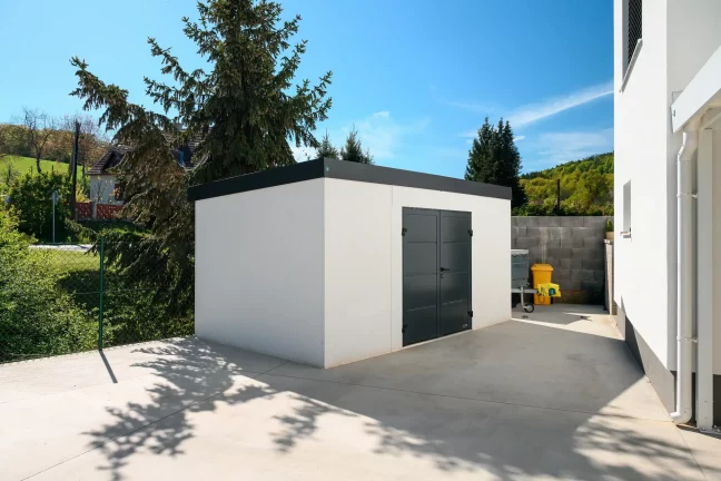 Modernes Gartenhaus mit anthrazitfarbenen Details und überdachtem Eingang