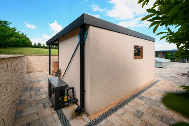 Gartenhaus auf einer gepflasterten Terrasse an einer Steinmauer