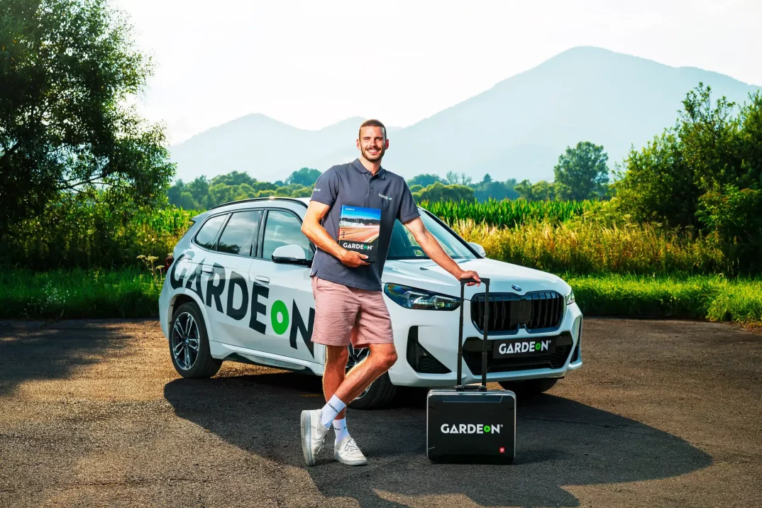 GARDEON-Mitarbeiter mit Musterbuch und Koffer am Firmen-BMW in der Natur.