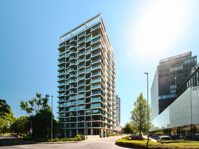 Modernes Hochhaus mit verglasten Balkonen und weißer Fassadenkonstruktion
