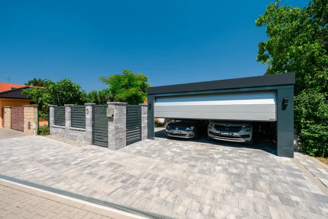 Carport mit geschlossenem Tor an einer gemauerten Einfriedung und Bäumen