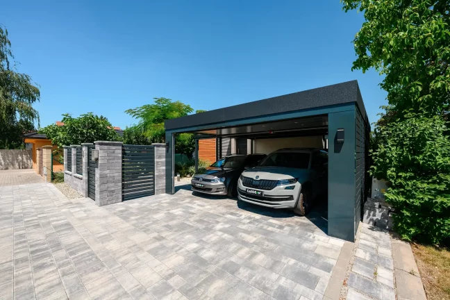 Blick auf den Carport mit zwei Autos hinter dem Zaun
