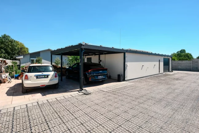 Vorderansicht des Hauses mit zwei Autos unter dem Carport