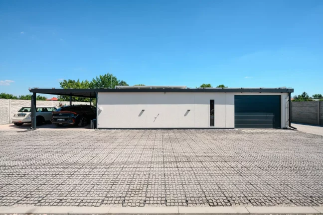 Vorderansicht des Hauses mit grünem GARDEON-Auto und Solarmodulen an der Wand