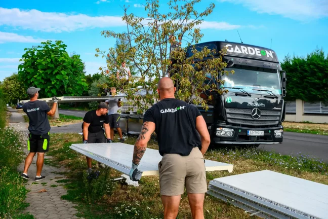 Monteure tragen weiße Sandwichpaneele vom Lkw über den Rasen