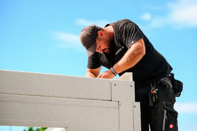 Mitarbeiter kontrolliert die obere Ecke der fertiggestellten weißen Garagenwand