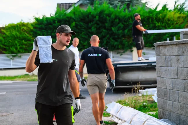 Monteur trägt ein verpacktes Paneel auf der Schulter entlang einer Steinmauer