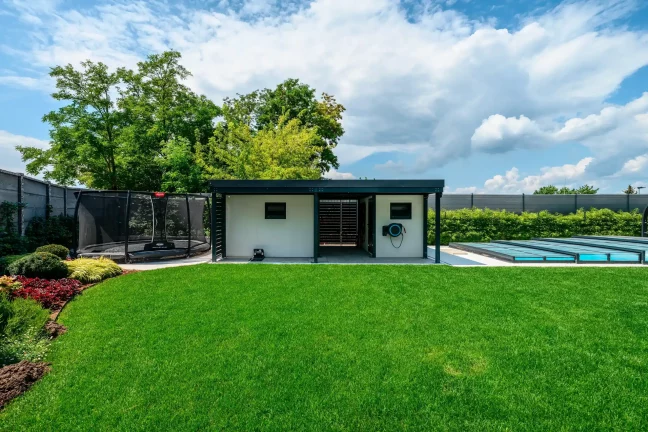 Weißes Gartenhaus mit Trampolin und abgedecktem Pool