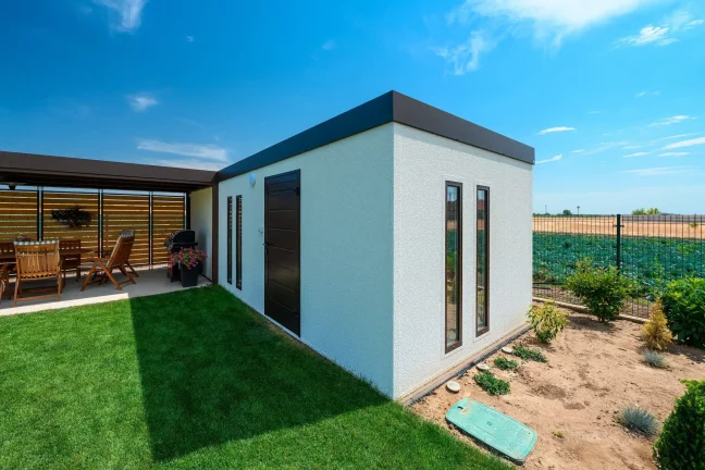 Detailansicht der Ecke des Gartenhauses mit dunkler Tür und zwei schmalen Fenstern