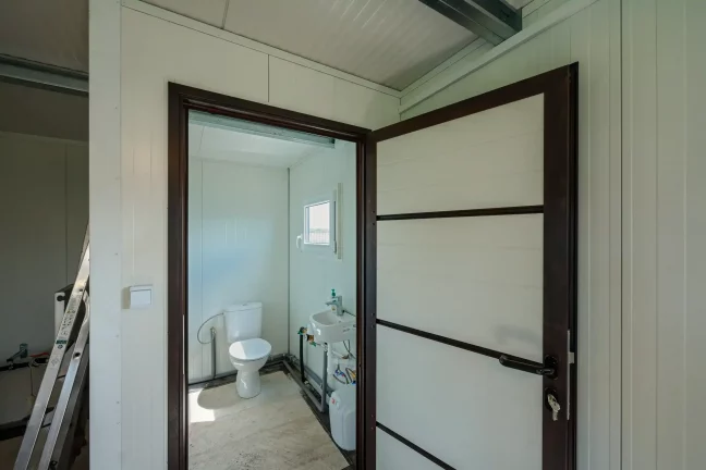 Blick durch die geöffnete Tür in ein kleines Badezimmer mit Toilette