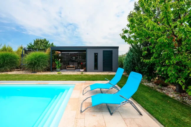 Gartenhaus mit überdachtem Sitzbereich, Pool und zwei blauen Sonnenliegen