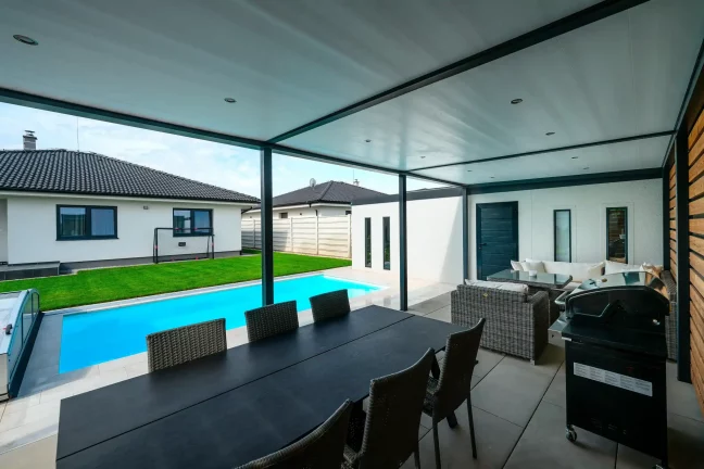 Ausblick unter der Pergola auf den Rasen, den Pool und das Gartenhaus