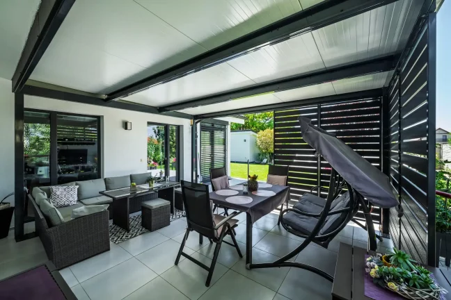 Esstisch, Stühle und Schaukelstuhl unter der Pergola