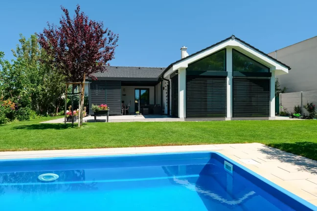 Blick auf das Haus mit verglaster Giebelwand und Lamellen