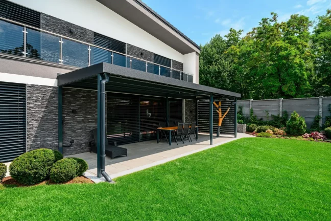 Pergola mit Esstisch am Haus mit Steinverkleidung