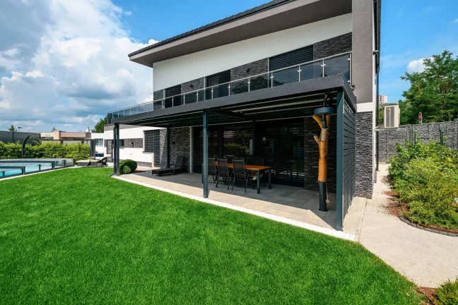 Seitenansicht des Hauses mit Pergola, Pool und Sonnenliege