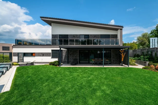 Rückansicht des zweistöckigen Hauses mit Balkon und Pergola