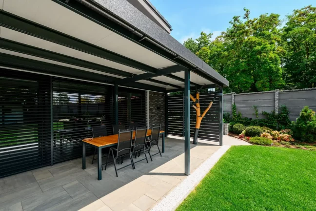Esstisch unter der Pergola mit einer Holzskulptur in Baumform