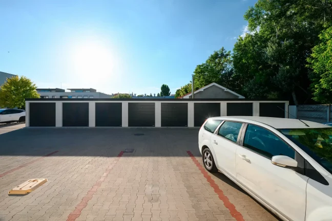 Blick auf eine Garagenreihe neben einem Zaun und einem Mehrfamilienhaus