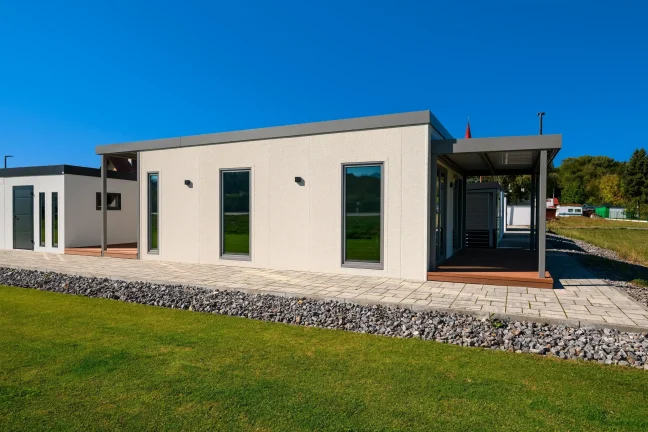 Hintere Ecke des Tiny Houses mit überdachtem Eingang und Holzterrasse